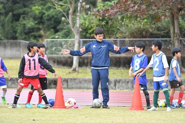 指導者が子供たちにサッカーを教える場面
